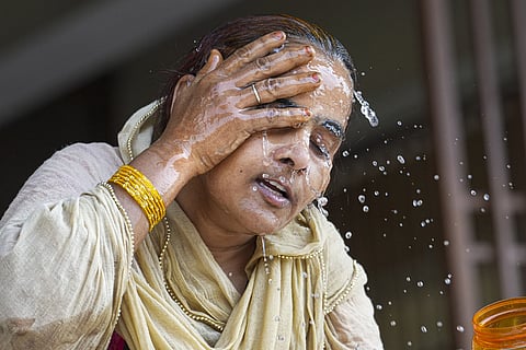 A woman splashes water on her face on a hot summer day.