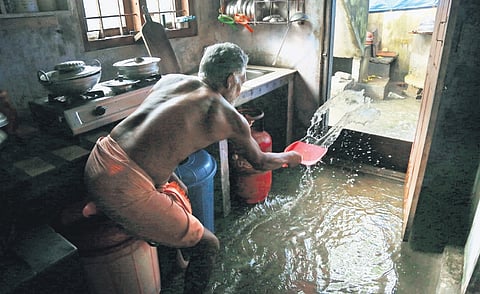 Babu Matteppilly tries to drain water from his kitchen using a dust pan at Pazhangad in Edavanakkad