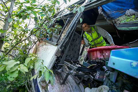 A forensic official inspects a bus that fell into a deep gorge on Sunday after being fired at by suspected militants in Reasi district, Jammu and Kashmir, Monday, June 10, 2024.