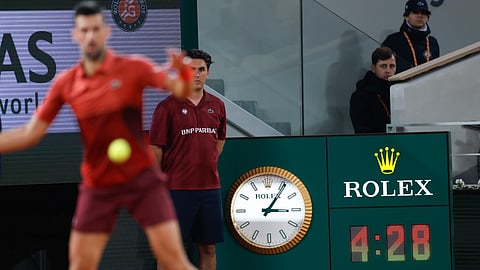 Serbia's Novak Djokovic plays a shot against Italy's Lorenzo Musetti as the clock indicates the match time played in the fifth set of their third round match of the French Open tennis tournament at the Roland Garros stadium in Paris, Sunday, June 2, 2024.