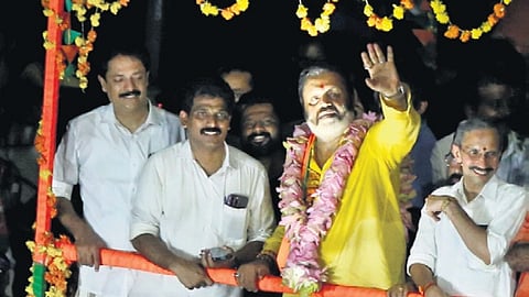 Thrissur MP-elect Suresh Gopi waves as his victory procession passes via Swaraj Round on Wednesday. BJP state general secretary M T Ramesh is also seen.