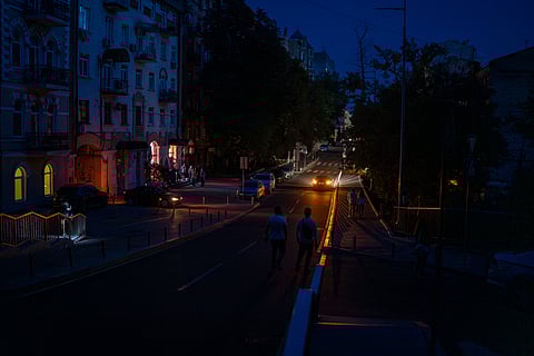 People walk along a road during a blackout in central Kyiv, Ukraine, Thursday, June 6, 2024.