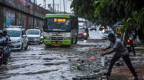A man retrieving a shopping cart which has swept away in rain water from a shopping mall into the flooded NH16 service road as heavy rain laesh Bhubaneswar on Tuesday.