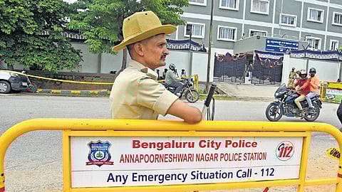 A constable keeps watch in front of Annapoorneshwari Nagar police station, where actor Darshan and his associates are held, on Friday