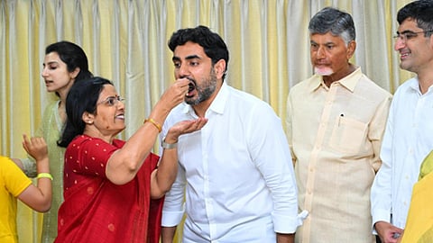 TDP chief and CM designate Nara Chandrababu Naidu and Party general secretary Nara Lokesh (seen eating cake) celebrate their party's win at their residence in Undavalli.