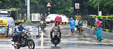 People shield themselves from moderate rains in Hyderabad on Thursday.