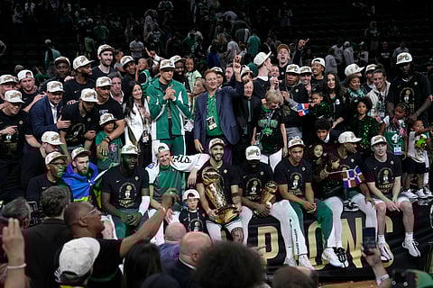 Boston Celtics forward Jayson Tatum (center) holds the Larry O'Brien Championship Trophy as he celebrates with the team after they won the NBA Finals 2024.