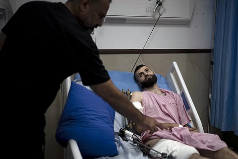 Raed Abadi, left, tends to his son, Mujahid Abadi 24, as he recovers from gunshot wounds and burns at the Ibn Sina Specialised Hospital in the West Bank City of Jenin, Tuesday , June 25, 2024.