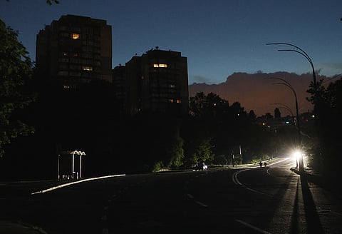 This photograph shows a car driving on a dark street during a partial electricity blackout in Kyiv