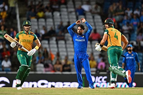 Afghanistan’s captain Rashid Khan (C) reacts as South Africa’s captain Aiden Markram (R) and South Africa’s Reeza Hendricks (L) run between wickets during the ICC men’s Twenty20 World Cup 2024 semi-final cricket match between South Africa and Afghanistan