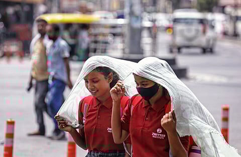 Girls cover their heads with a piece of cloth to protect themselves from scorching heat on a hot summer day