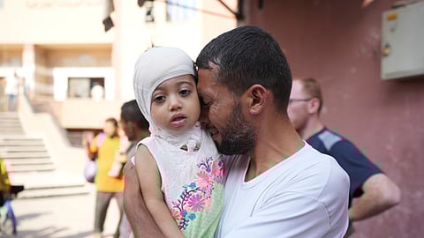 A Palestinian man reacts as he says goodbye to his sick daughter before leaving the Gaza Strip to get treatment abroad through the Kerem Shalom crossing, in Khan Younis, southern Gaza Strip.