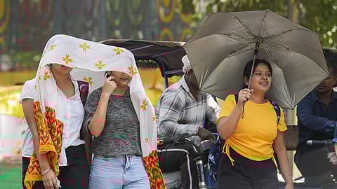 Women take cover under a scarf on a hot summer day amid heatwave, in New Delhi