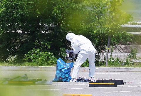 An officer wearing protective gear collects the trash from a balloon presumably sent by North Korea, in Siheung, South Korea, Sunday, June 2, 2024.