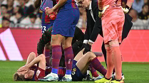 Barcelona's Dutch midfielder Frenkie de Jong lies on the ground injured during the Spanish league football match between Real Madrid CF and FC Barcelona at the Santiago Bernabeu stadium in Madrid on April 21, 2024.