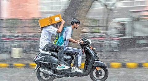 Youngsters rushing on a two-wheeler amid heavy rains in New Delhi on Saturday