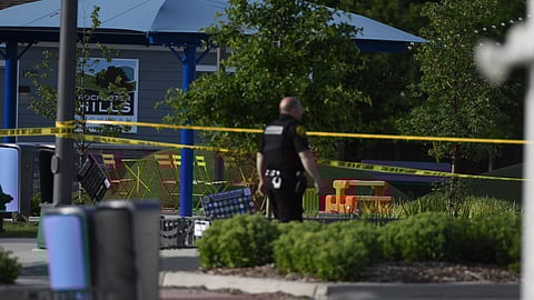 A police officer walks across the plaza of the Brooklands Plaza Splash Pad in Rochester Hills, Mich., where police say there was an active shooter Saturday.