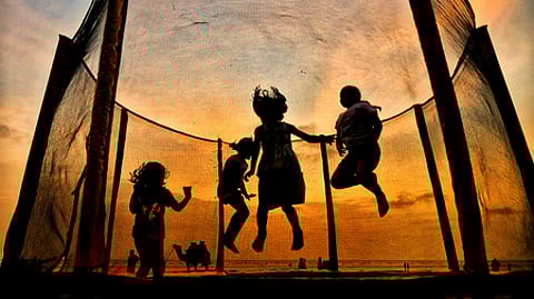 Children jump on a trampoline on the backdrop of sunset as they enjoy their summer vacations, at Bhuigaon Beach in Mumbai.
