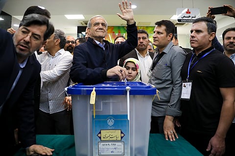 In this photo provided by Iranian Students' News Agency, ISNA, reformist candidate for the Iranian presidential election Masoud Pezeshkian casts his ballot as he waves to media in a polling station.