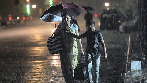 A pedestrian uses an umbrella to shield herself during rains, outside CSMT in Mumbai, Sunday.