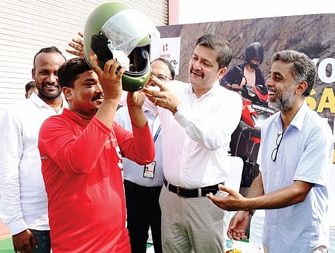 Transport commissioner Amitabh Thakur helps a Zomato delivery partner wear a helmet at Rasulgarh square.