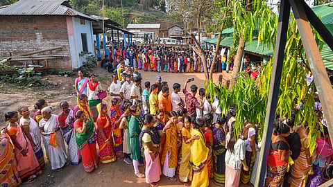 People wait to cast their votes for the 2nd phase of Lok Sabha elections, in Morigaon, Assam.