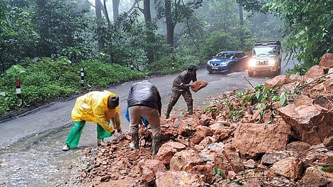 Forest department staff clearing rocks that were accumulated on the road due to a landslide near Kaithakolli highway road in Pandalur Taluk on Thursday.