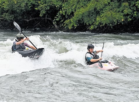Participants of the International Whitewater Kayaking Freestyle Competitions wade through the Kuttiyadi river