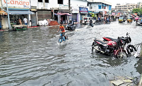 Vehicle riders wading through an inundated road in Vizag on Friday