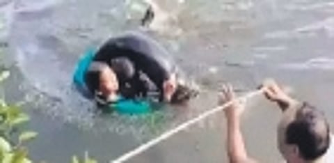 Locals rescue the occupants of a car that was driven into the Imamguda lake in Abdullapurmet on Wednesday