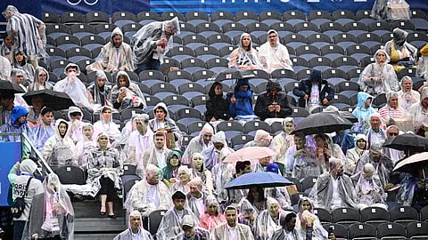 Spectators in rain gear wait for the start of the opening ceremony for the 2024 Summer Olympics in Paris.