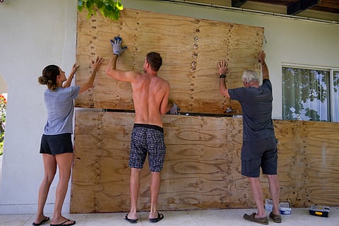 Residents cover the windows of their home in preparation for the arrival of Hurricane Beryl.