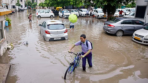 A boy pushes his bicycle on a waterlogged road after heavy monsoon rainfall, in Ahmedabad on July 29, 2024.