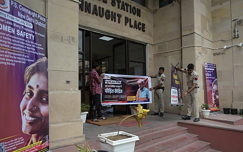 Police personnel install posters about the new criminal laws put up outside Connaught Place Poloce Station to create awareness among the people, in New Delhi on Monday.