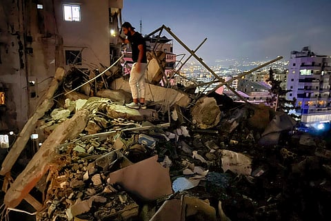 People walk near the building that was hit by an Israeli airstrike in the southern suburbs of Beirut, Lebanon