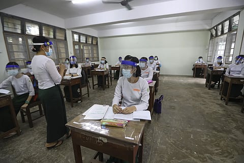A teacher and students wearing face shields and masks attend a class by keeping social distancing at a high school in Yangon , Myanmar, July 21, 2020.