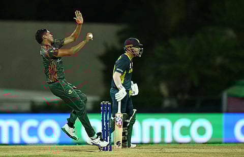 Bangladesh's vice-captain Taskin Ahmed (L) bowls as Australia's David Warner looks on during the ICC men's Twenty20 World Cup 2024 Super Eight cricket match between Australia and Bangladesh on June 20, 2024.