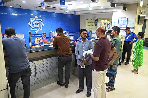 People stand in queues while visiting a bank in Dhaka on July 24, 2024