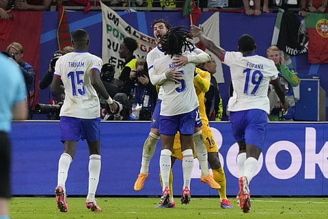 Theo Hernandez of France, top center, and Jules Kounde celebrate after Hernandez scored the deciding goal in a shootout to win a quarter final match against Portugal at the Euro 2024 soccer tournament in Hamburg, Germany, Friday, July 5, 2024.