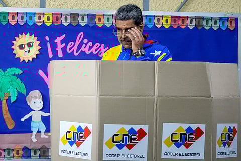 President Nicolas Maduro adjusts his glasses to mark his ballot for the presidential elections in Caracas, Venezuela, Sunday, July 28, 2024.