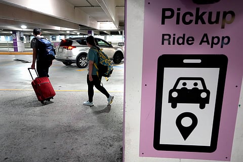 Travelers enter a pick up location for ride-hailing companies, Tuesday, July 9, 2024, in the lower level of a parking garage at Logan International Airport, in Boston.