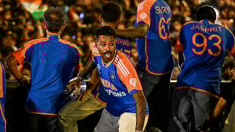 Hardik Pandya (C) holds the Hardik Pandya holds the World Cup trophy as he greets fans during an open bus roadshow in Mumbai