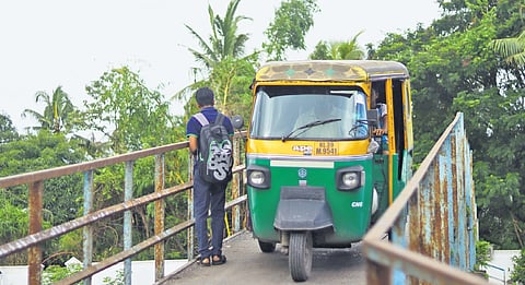An autorickshaw passes through the narrow bridge meant for pedestrians