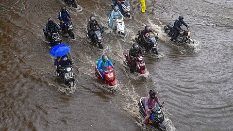 Commuters wade through a waterlogged street following rains, in Mumbai.