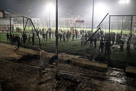 Residents and authorities stand at a soccer field that was hit by a rocket, killing multiple children and teenagers, in the Druze town of Majdal Shams, in the Israeli-annexed Golan Heights.