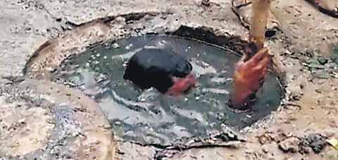 Worker cleaning a manhole by submerging himself in sewage in Cuddalore