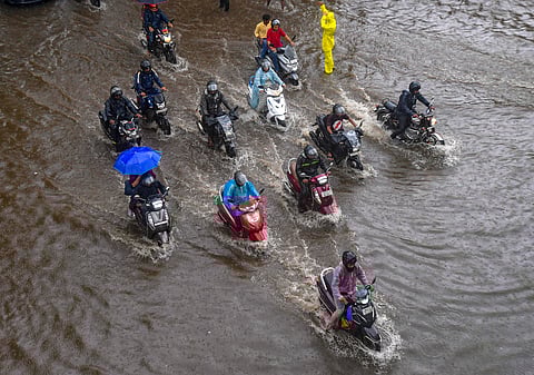 Commuters wade through a waterlogged street following rains, in Mumbai.