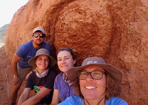 In this undated photo provided to the Associated Press by Stellenbosch University researcher, Michele Francis, right, and other researchers, pose for a selfie, next to an ancient termite mound in Namaqualand, South Africa.
