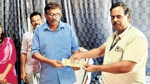 Shefeeq I, district coordinator of KSRTC Budget Tourism Cell, Alappuzha, hands over a ticket of the Nehru Trophy Boat Race to Assistant Transport Officer Ajith A during the opening of a dedicated boat race ticket counter at the Alappuzha depot