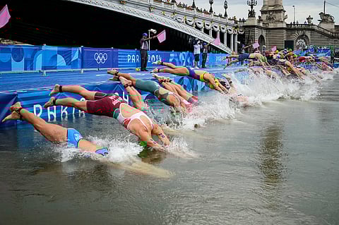 Athletes dive into the water for the start of the women's individual triathlon competition at the 2024 Summer Olympics.